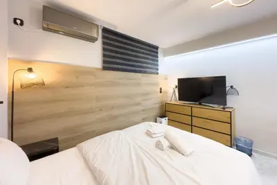 a bedroom with a white bed and a television at Stylish & Elegant Apt in Pagrati in Athens