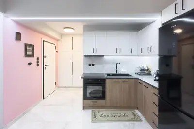 a kitchen with white cabinets and a black stove at Stylish & Elegant Apt in Pagrati in Athens