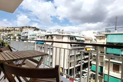 a balcony with a wooden table and a view of a city at Cozy Athenian 2BD Apt Top Floor Panoramic View in Athens