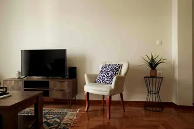 a living room with a chair and a television at Cozy Athenian 2BD Apt Top Floor Panoramic View in Athens