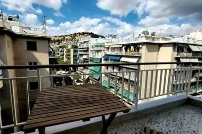 a wooden deck on a balcony with buildings at Cozy Athenian 2BD Apt Top Floor Panoramic View in Athens