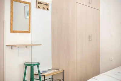 a bedroom with a green stool and a cabinet at Cozy Acropolis Studio in the heart of Athens in Athens