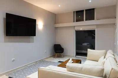 a living room with a white couch and a television at South Glyfada Downtown49 Apartment in Athens