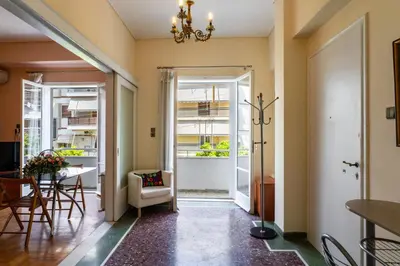 a hallway with a table and chairs and a chandelier at Neos kosmos Filimon in Athens