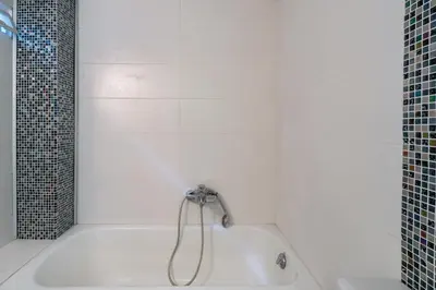 a white bath tub with a shower in a bathroom at Neos kosmos Filimon in Athens