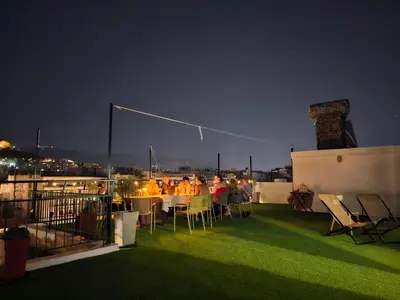 a group of people sitting at tables on a balcony at night at Lycabettus View Kaniggos in Athens