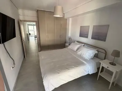 a bedroom with a white bed and a television at Central Apartment with private parking in Athens