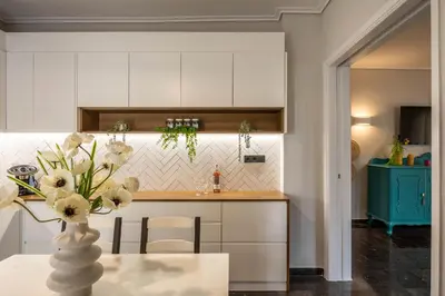 a kitchen with white cabinets and a vase with flowers on a table at Comfy and calm apartment near the beach in Athens