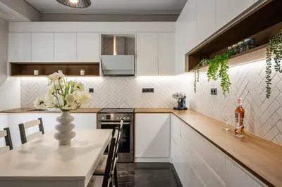 a kitchen with white cabinets and a vase of flowers on a table at Comfy and calm apartment near the beach in Athens