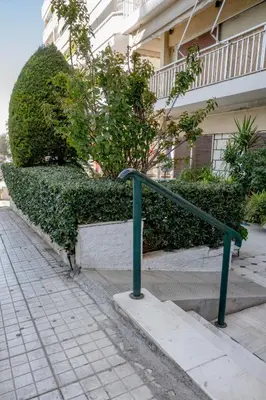 a green railing on a sidewalk next to a building at Flisvos Halcyon in Athens