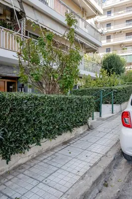 a white car parked next to a hedge in front of a building at Flisvos Halcyon in Athens