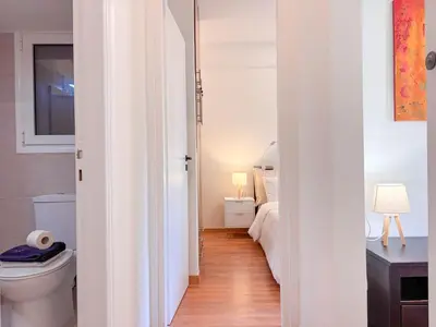 a white bathroom with a toilet and a bedroom at Restful Flat in Glyfada Center in Athens