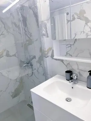 a white bathroom with a shower and a sink at Varkiza Zen Space in Vari