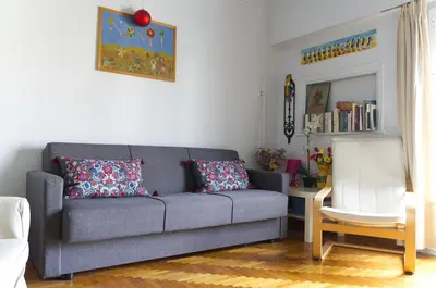 a living room with a gray couch and a white chair at Funky Apartment in Athens