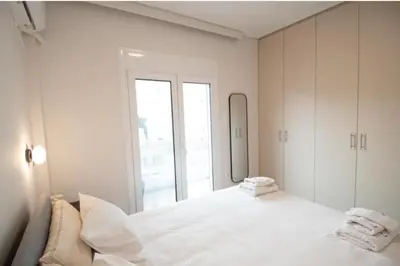 a white bedroom with a large bed and a window at Olympian Zeus top location in Athens