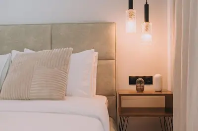 a bed with white pillows and a night stand with a side table at Elegant Penthouse 2 BRs - Large Veranda with View in Athens