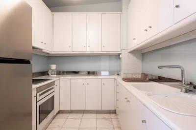 a white kitchen with white cabinets and a sink at The Acropolis Mansion in Athens