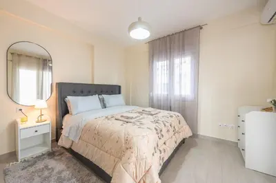 a white bedroom with a bed and a mirror at Casa Ilioupoli in Athens