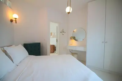 a white bedroom with a white bed and a mirror at Bunny Island Exquisite Villas in Lagonissi