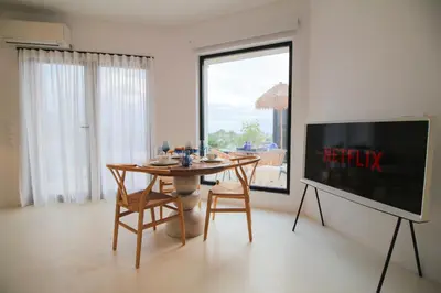 a dining room with a table and a tv at Bunny Island Exquisite Villas in Lagonissi
