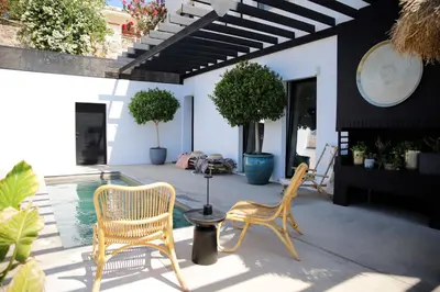 a patio with two chairs and a swimming pool at Bunny Island Exquisite Villas in Lagonissi
