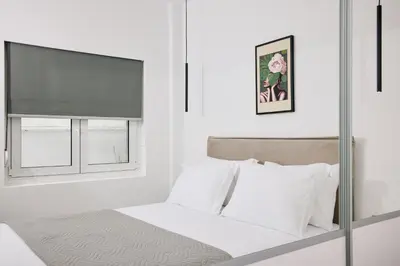 a white bedroom with a bed and a window at La Stella Apartment Thisio in Athens
