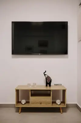 a television on a white wall with a vase on a table at La Stella Apartment Thisio in Athens