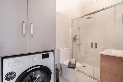 a washing machine in a bathroom with a shower at Kalamaki Beach Apartment in Athens