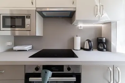 a kitchen with white cabinets and a stove top oven at Kalamaki Beach Apartment in Athens