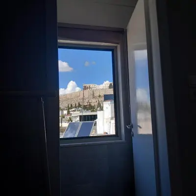 a window in a room with a view of a city at Super central loft - Acropolis metro, museum in Athens