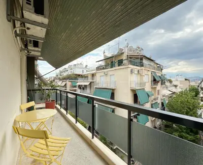 a balcony with two chairs and a table and a building at Athina in Athens 5 min to Metro Station in Athens