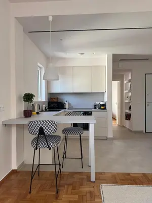 a white kitchen with two chairs and a counter at Athens Riviera Sea in Athens