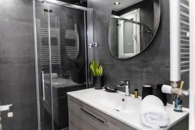 a bathroom with a sink and a shower with a mirror at 3BD Family Comfort Stay in Athens
