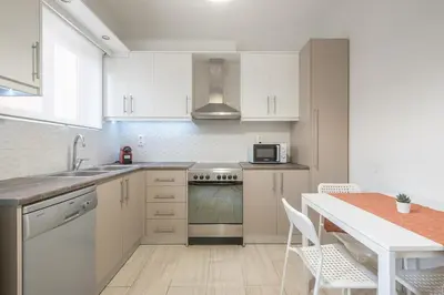 a kitchen with white cabinets and a table with chairs at Kallithea metro station in Athens