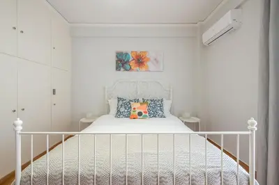 a bedroom with a white bed with a white headboard at Kallithea metro station in Athens