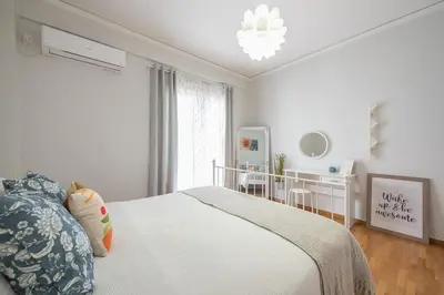 a white bedroom with a bed and a chandelier at Kallithea metro station in Athens