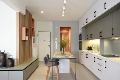 a kitchen with white cabinets and a table and chairs at The Athens Urban Loft in Athens