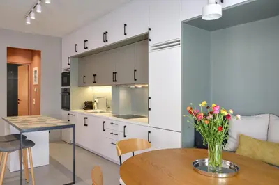 a kitchen with white cabinets and a table with flowers at The Athens Urban Loft in Athens