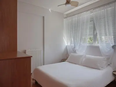 a white bedroom with a bed and a window at Evi's Voula Home in Athens