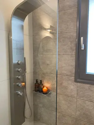 a shower with a candle on a shelf in a bathroom at The Twin Residences in Kallithea in Athens