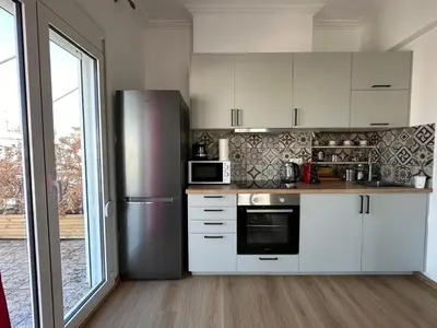 a kitchen with white cabinets and a stainless steel refrigerator at 6th Floor Skyline Suite with Spectacular View in Athens