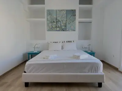 a white bedroom with a bed with two blue tables at 6th Floor Skyline View Studio 2 in Athens in Athens