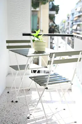a table and chairs on a balcony with a potted plant at Brand new 3bedroom athenian flat in Koukaki in Athens