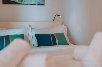a bed with white sheets and pillows in a room at Elegant Intimate Studio in Piraeus near Pasalimani in Piraeus