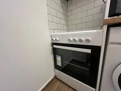 a white oven in a kitchen with white tiles at Cozy apartment in Athens in Athens