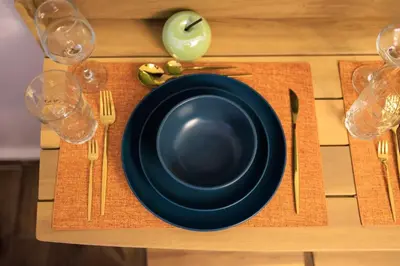 a black plate on a wooden table with forks and knives at Aiolos Lux and Easy suite near the sea alimos in Athens