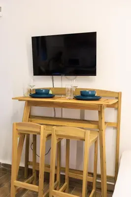 a wooden table with two chairs and a television on a wall at Aiolos Lux and Easy suite near the sea alimos in Athens