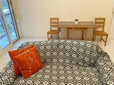 a couch with an orange pillow next to a table at Bluebay comfort apartment Paleo Faliro in Athens