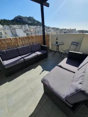 a patio with a couch and a table on a roof at Penthouse! Best views Lycabetous & Parthenon ! EXARCHEIA in Athens