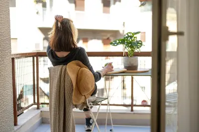 a woman sitting at a table looking out the window at LIV - Marvelous Apartment Near Acropolis in Athens